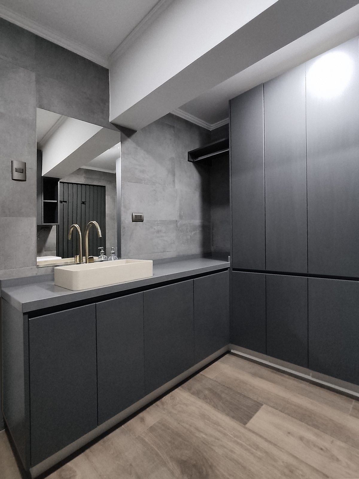 Baño remodelado con mueble de lavamanos oscuro y piso de madera